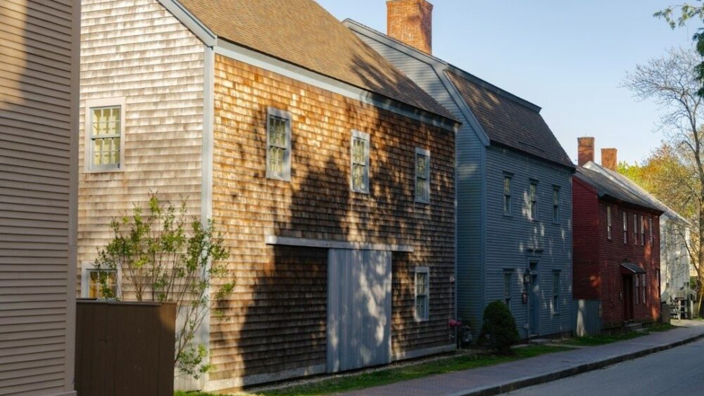 Historic wood-shingled New England homes lining a narrow sidewalk