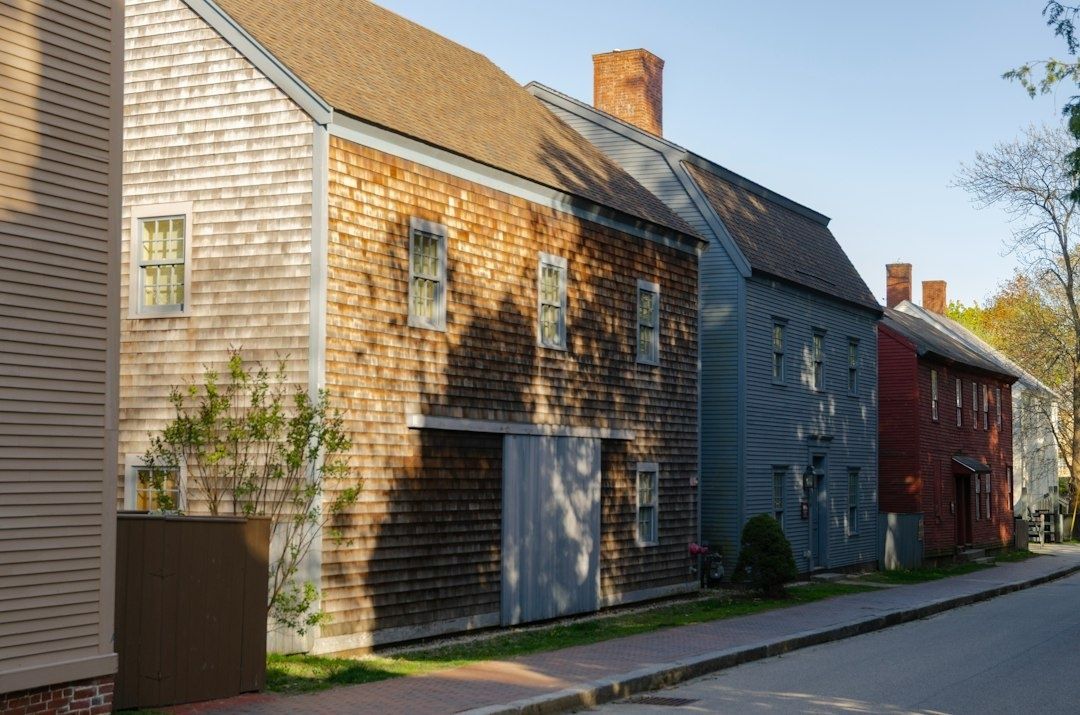 Historic wood-shingled New England homes lining a narrow sidewalk