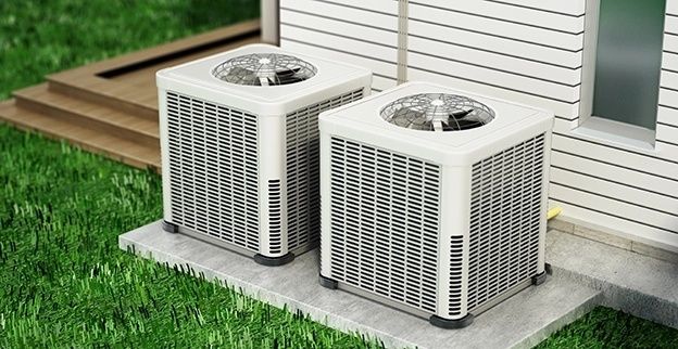 Two outdoor heat pump units beside a white-sided residential home