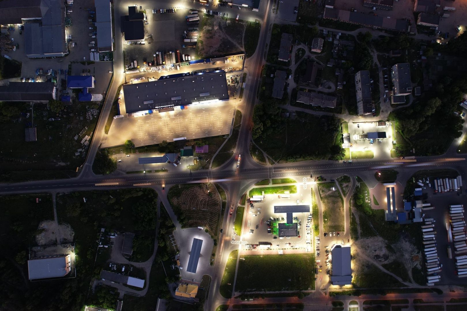 Aerial nighttime view of roads, buildings, parking lots, and sparse greenery