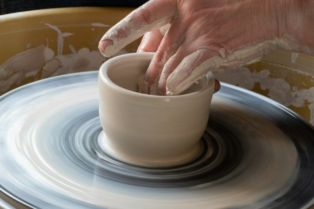 Potter's hands shape a clay vessel on a spinning wheel