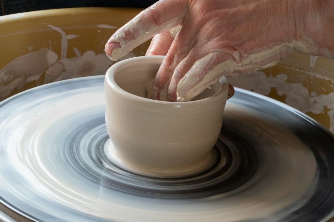 Potter's hands shape a clay vessel on a spinning wheel
