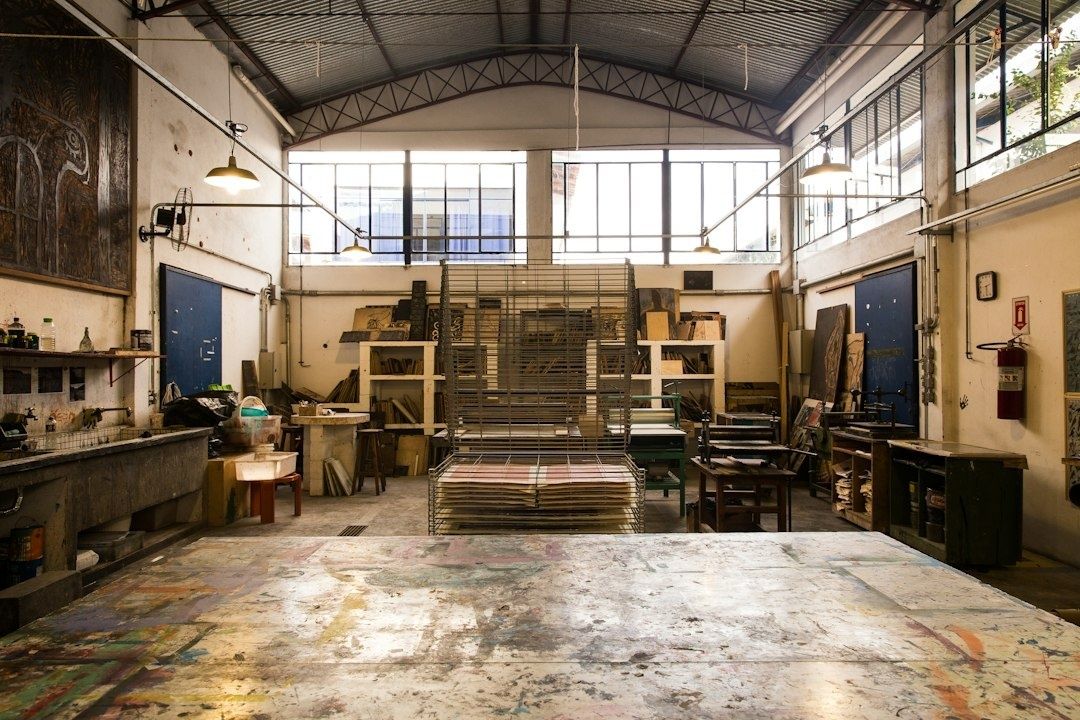 Industrial art studio with printmaking tables, racks, and large windows